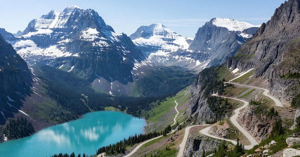 Going-to-the-Sun Road winding through Glacier National Park's alpine terrain with snow-capped peaks and turquoise lake below