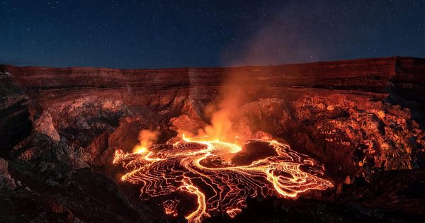Glowing lava lake inside Halemaʻumaʻu Crater at night, illuminating the caldera walls of Kīlauea in Hawaii Volcanoes National Park