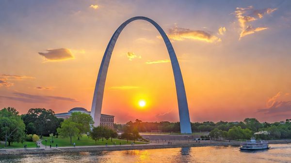 Gateway Arch curving above the Mississippi River at sunset, St. Louis
