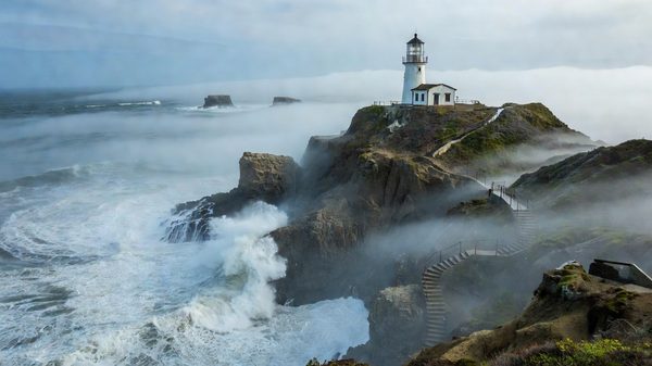 Point Reyes lighthouse on rocky Pacific headland above rolling fog