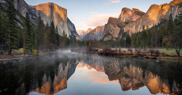 Yosemite Valley at sunrise with El Capitan and Half Dome reflected in the Merced River, golden light on granite walls